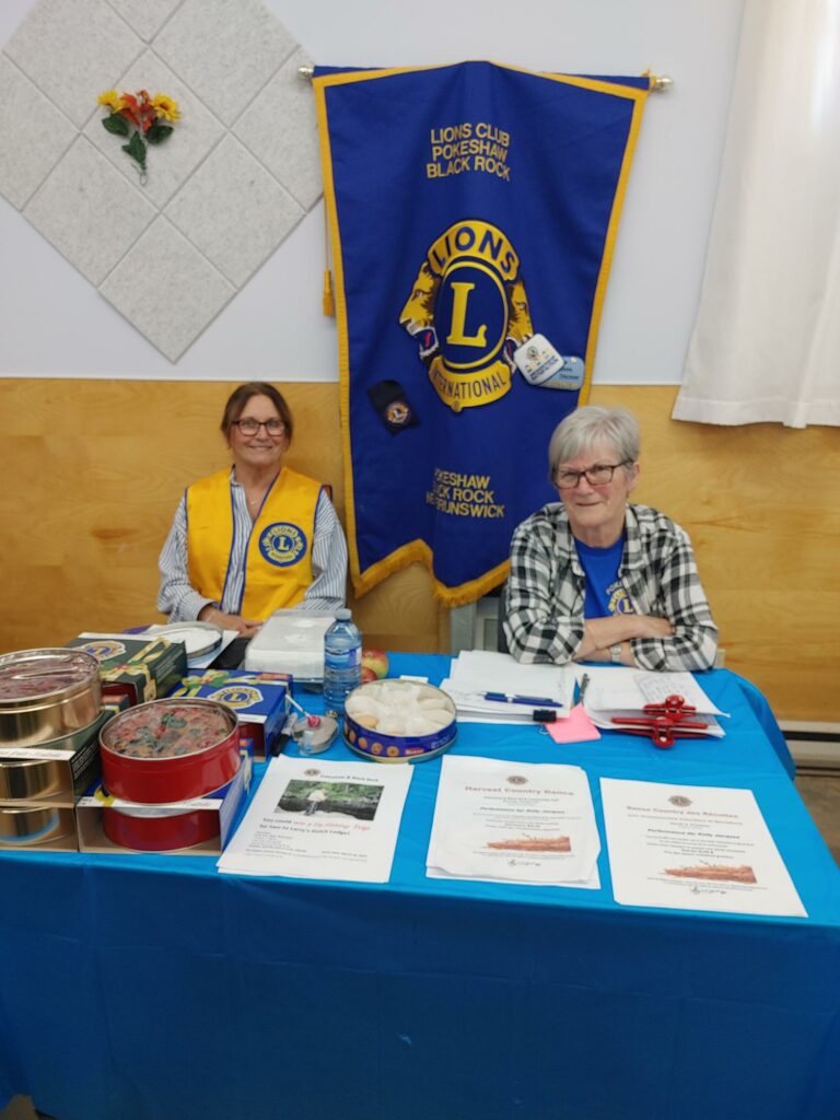 Lion Viola Riordon and Lion Lillian Riordon, selling Lion fruit cakes and tickets to the Harvest Country Dance at the Cranberry Festival 2024.